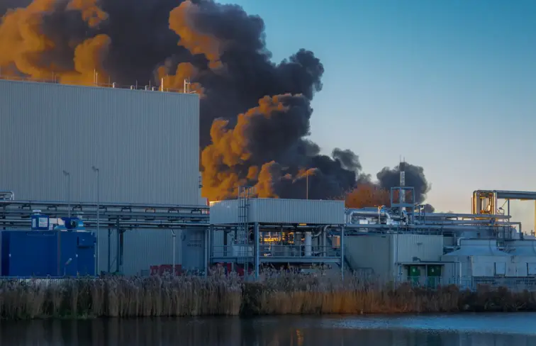 Uma fábrica a arder a sair fumo.